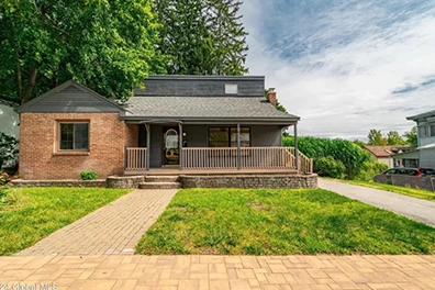 Charming brick house with a welcoming front porch and landscaped lawn.