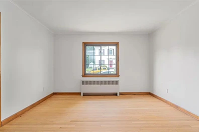 Empty room with hardwood floors, white walls, window, and radiator, ready for a tour.