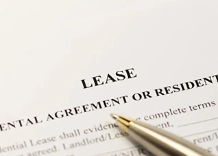 Lease agreement document with a pen, showing "LEASE" text. Leasing.