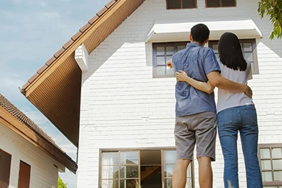 Couple looking at a white house, thinking about a property search.