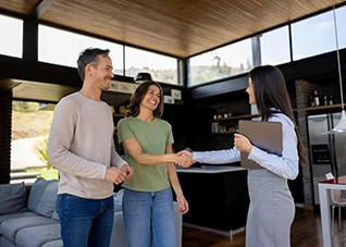 Couple shaking hands with a real estate agent during property tours of a modern home.