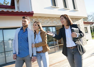 Realtor showing property tours to a young couple at a modern home.