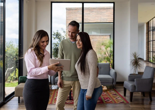 Realtor showing residential property to couple on tablet. Sales opportunity.