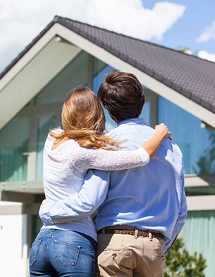 Couple embracing in front of a modern home, looking towards the future.
